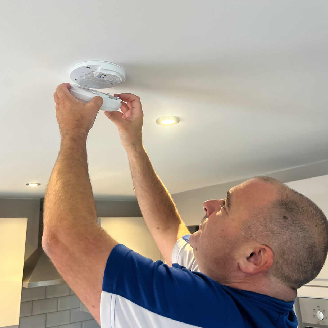 Smoke alarm installer fitting an alarm in a Chichester property